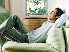 Mann sitzt entspannt auf einer Couch