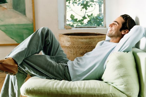 Mann sitzt entspannt auf der Couch