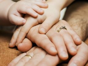 Familie legt Hände auf dem Tisch aufeinander