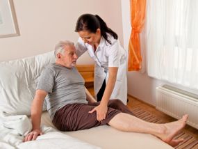 Krankenschwester hilft älterem Mann aus dem Bett
