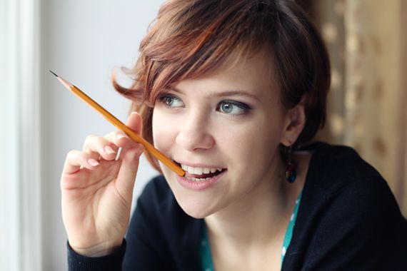 unge Frau, die nachdenkend auf einem Bleistift kaut.