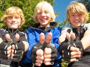 Drei Jungen mit Fahrradschutzkleidung lachen in die Kamera.