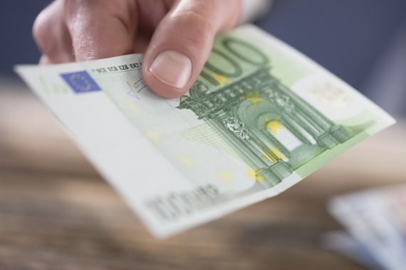 Eine reicht einen Hundereuroschein in Richtung Kamera