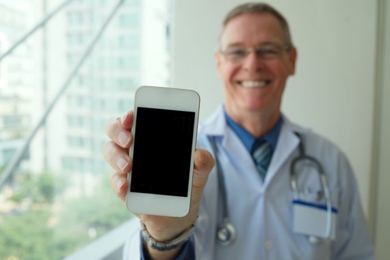 Arzt hält sein Smartphone in die Kamera