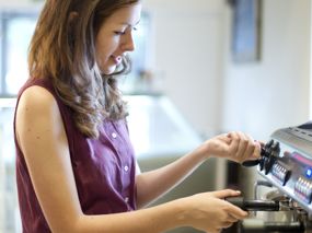 Junge Frau bedient Kaffeemaschine