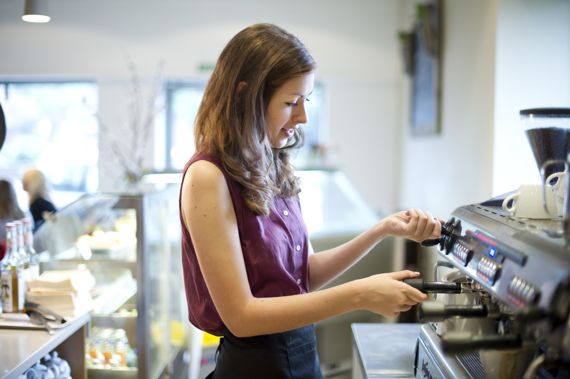 Junge Frau bedient Kaffeemaschine