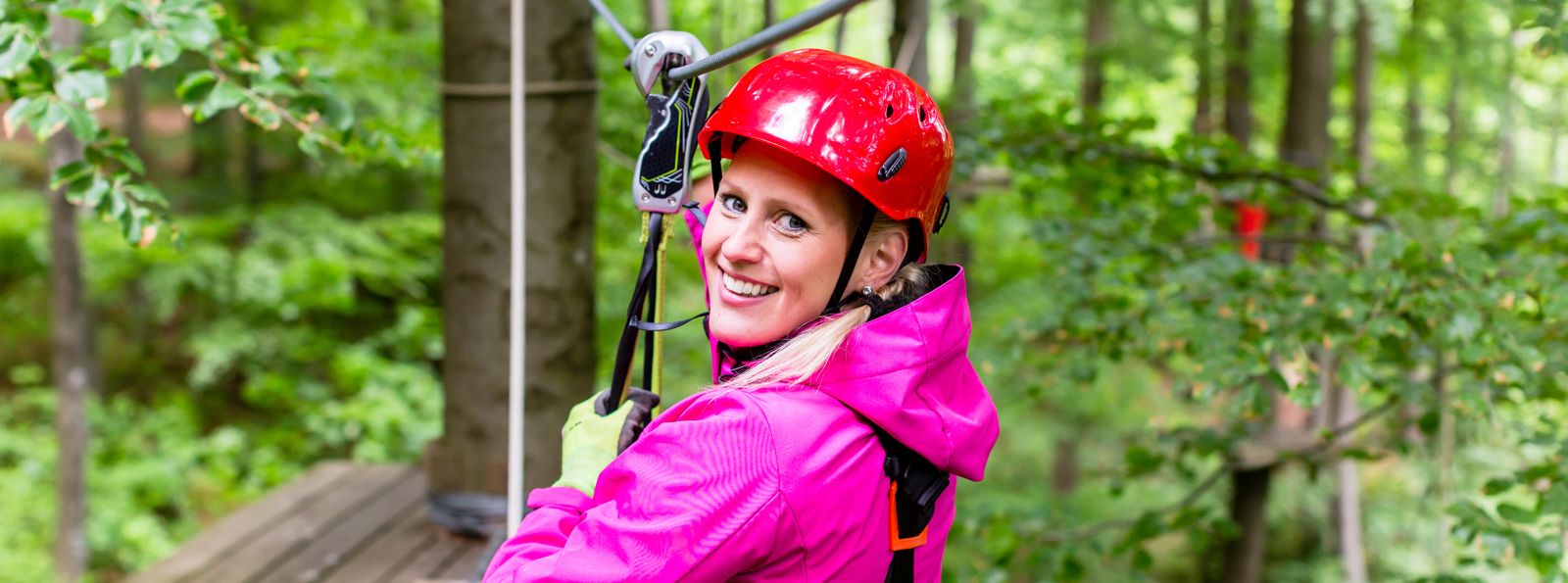 Frau in Hochseilgarten gesichert an Drahtseil