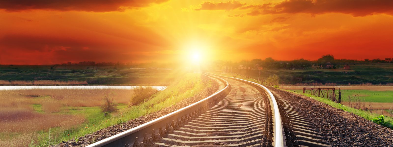 Schiene führt durch Landschaft bei Sonnenuntergang