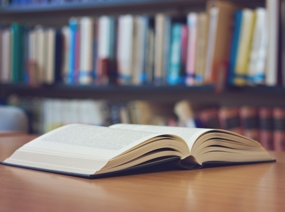 Aufgeschlagenes Buch liegt auf einem Tisch in einer Bibliothek