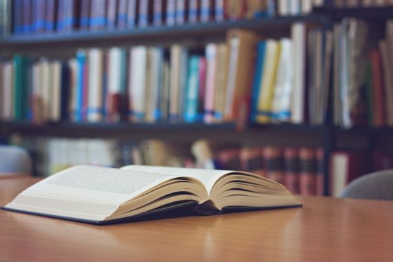 Aufgeschlagenes Buch liegt auf einem Tisch in einer Bibliothek