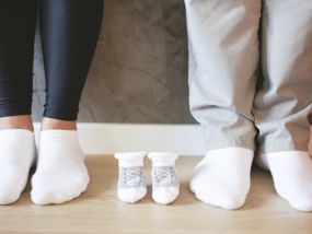Socken für Baby in der Mitte von Mama und Papas Füßen