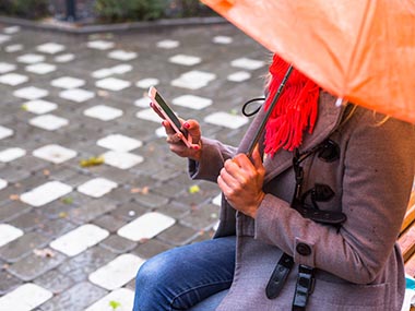 Frau mit Regenschirm und Smartphone