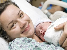 Glückliche Mama mit Neugeborenem auf der Brust