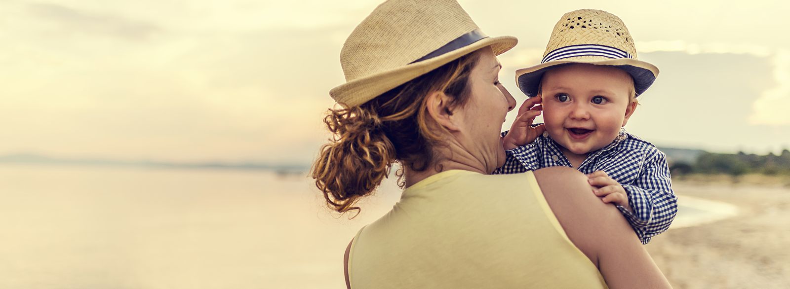 Mutter mit Baby auf dem Arm am Strand