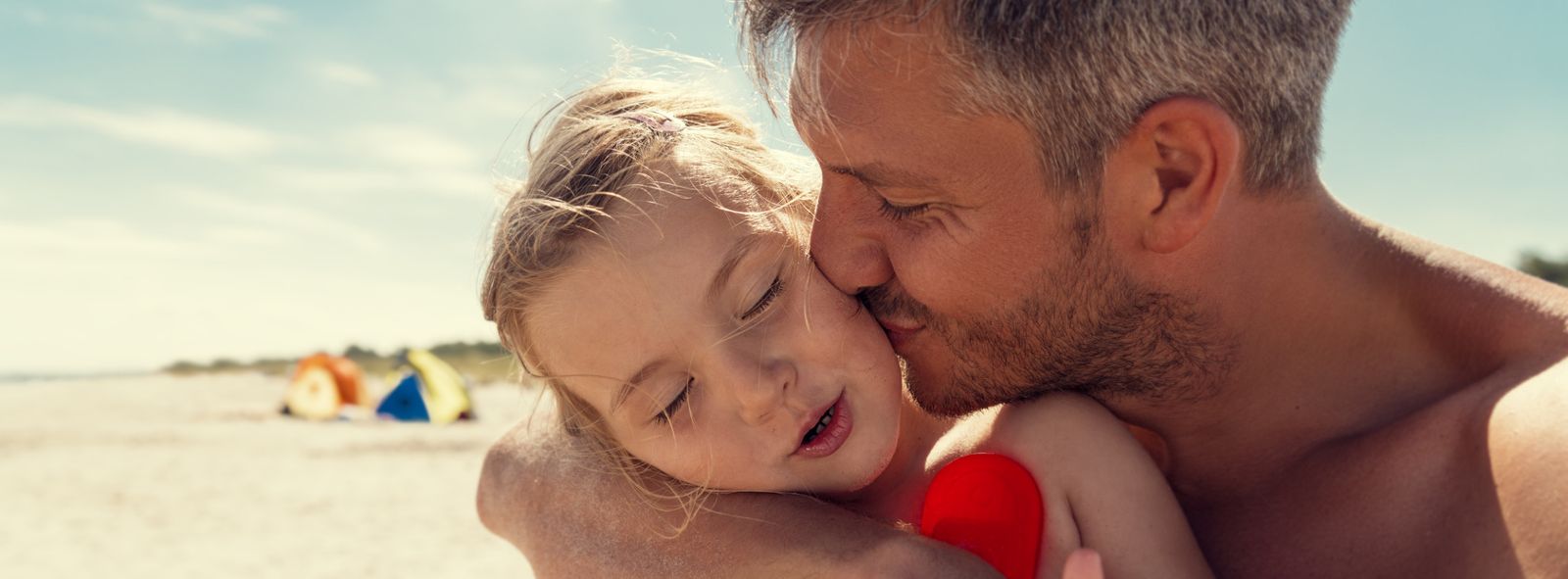 Vater umarmt Mädchen am Strand