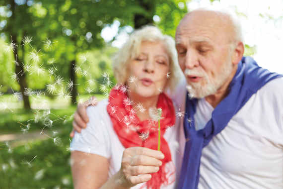 älteres Paar bläst auf eine Pusteblume